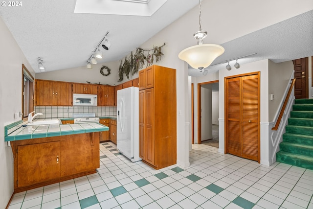 kitchen featuring decorative backsplash, white appliances, lofted ceiling with skylight, sink, and tile countertops