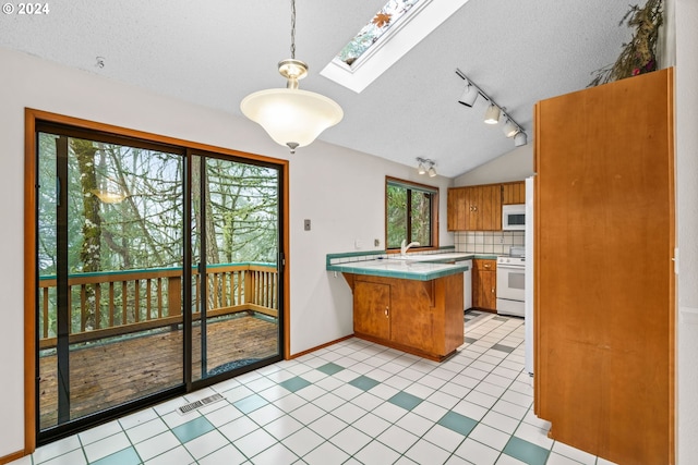 kitchen featuring kitchen peninsula, decorative backsplash, vaulted ceiling with skylight, white appliances, and decorative light fixtures