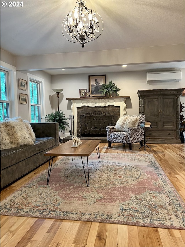 living room featuring a textured ceiling, hardwood / wood-style flooring, a wall unit AC, and a notable chandelier