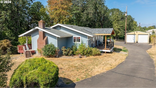 view of front of property with covered porch, a garage, and an outbuilding