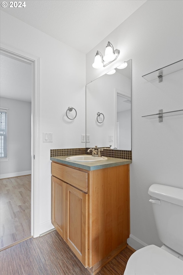 bathroom with hardwood / wood-style floors, vanity, and toilet