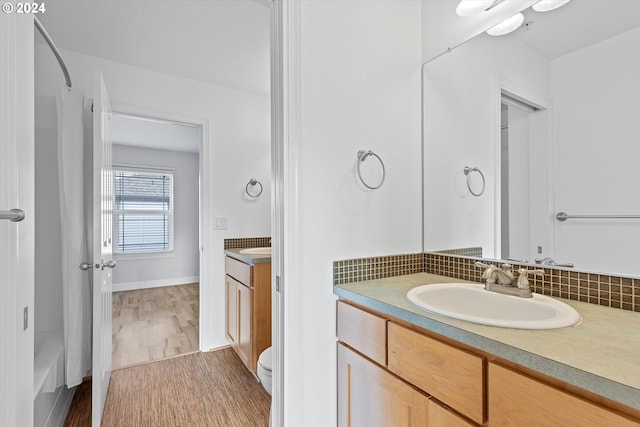 bathroom with decorative backsplash, vanity, wood-type flooring, and toilet