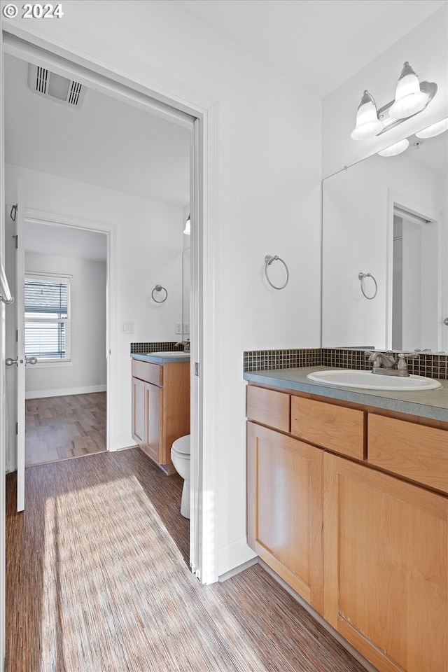 bathroom with toilet, vanity, and hardwood / wood-style flooring