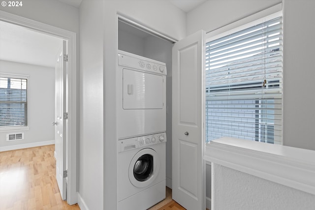 washroom featuring wood-type flooring and stacked washer / dryer