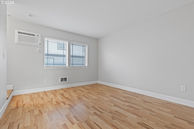 spare room featuring light hardwood / wood-style flooring and a wall unit AC