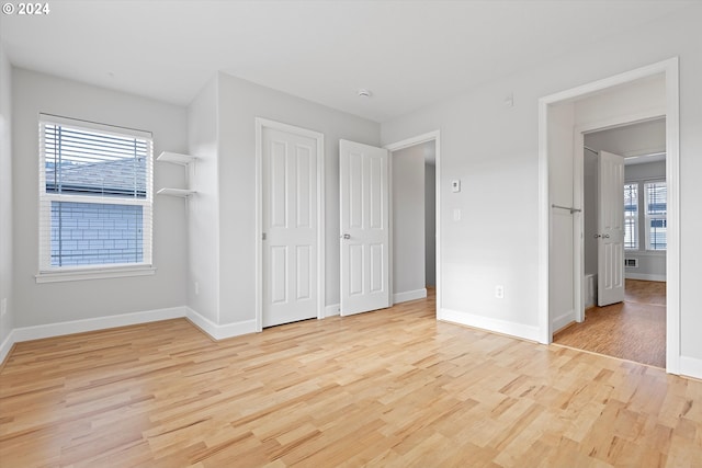 unfurnished bedroom with multiple windows and light wood-type flooring