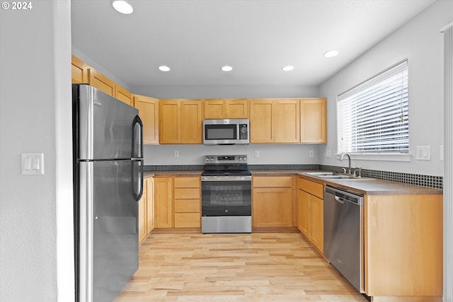 kitchen with appliances with stainless steel finishes, light hardwood / wood-style flooring, light brown cabinetry, and sink