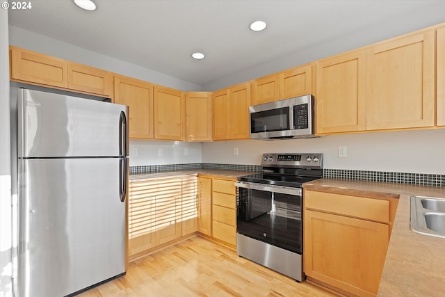 kitchen with sink, light brown cabinets, stainless steel appliances, and light wood-type flooring