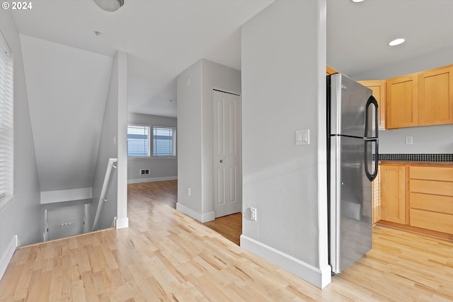 kitchen with stainless steel fridge, light hardwood / wood-style floors, and light brown cabinets