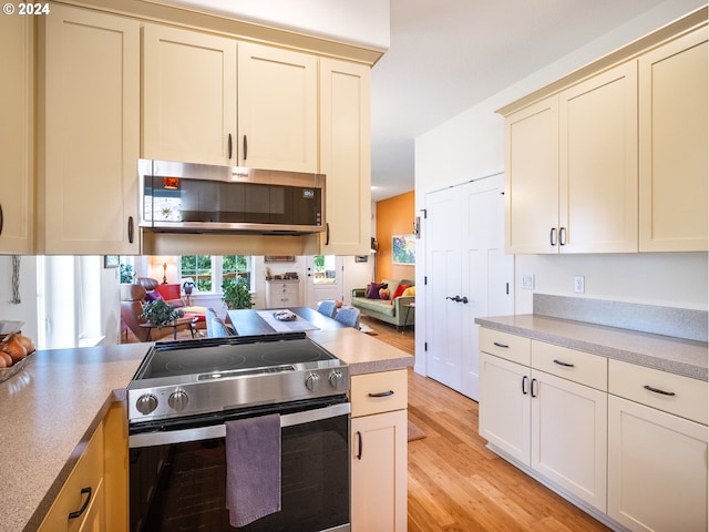 kitchen with cream cabinetry, appliances with stainless steel finishes, and light wood-type flooring