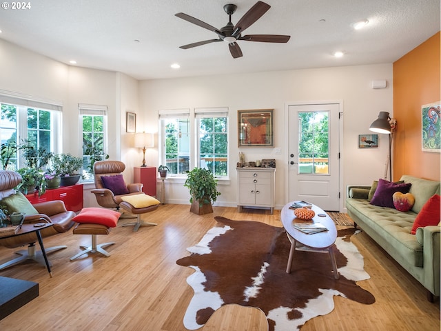 living room with ceiling fan, a textured ceiling, and light wood-type flooring