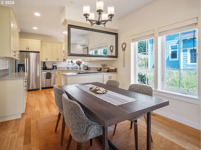 dining area with an inviting chandelier, light wood-type flooring, and a wall mounted AC