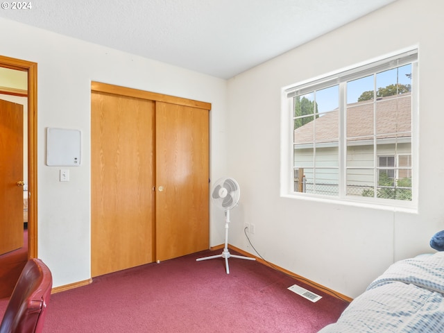 carpeted bedroom featuring a textured ceiling and a closet