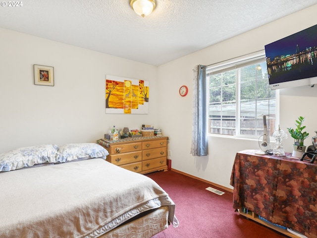 bedroom with a textured ceiling and dark colored carpet