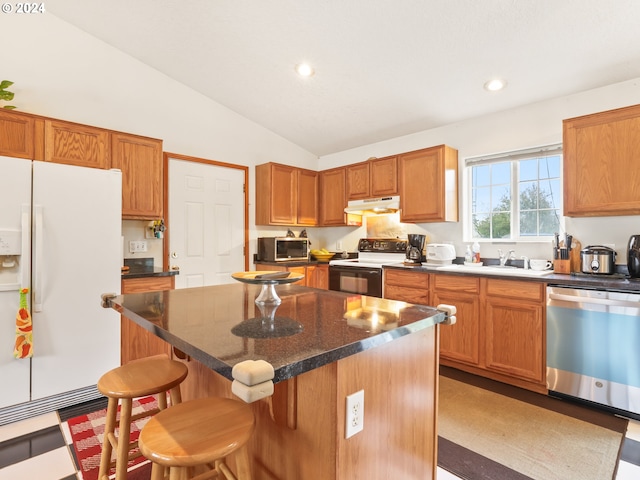 kitchen featuring sink, a breakfast bar area, vaulted ceiling, a kitchen island, and stainless steel appliances