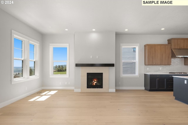 kitchen featuring backsplash, light wood-type flooring, and a fireplace