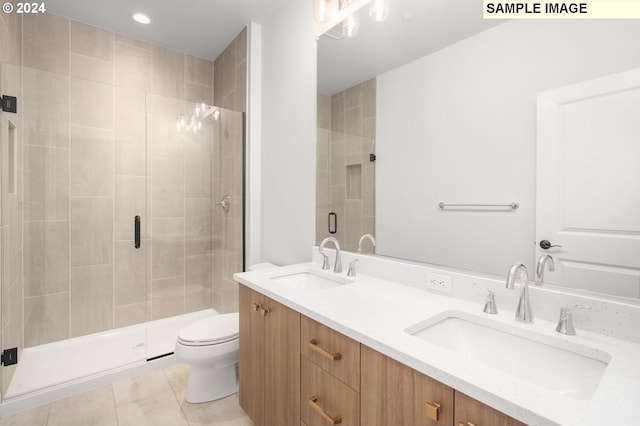 bathroom featuring tile patterned flooring, vanity, a shower with shower door, and toilet