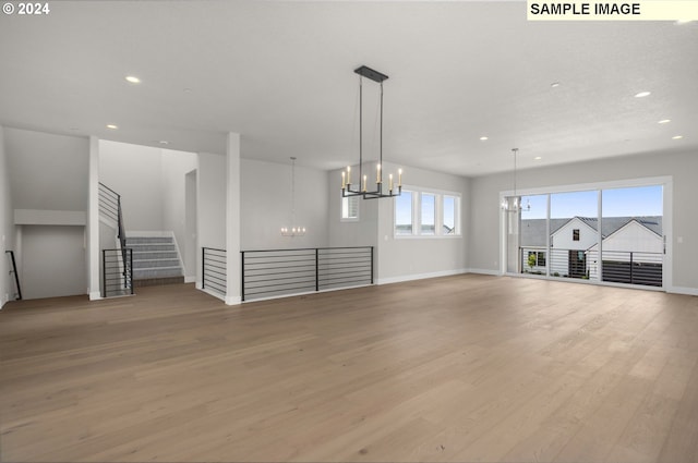 unfurnished living room with light wood-type flooring and a notable chandelier