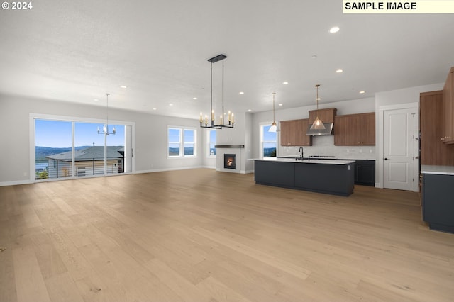 unfurnished living room featuring a mountain view, light wood-type flooring, sink, and an inviting chandelier