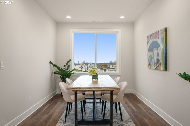 dining space with dark wood-type flooring, visible vents, and baseboards