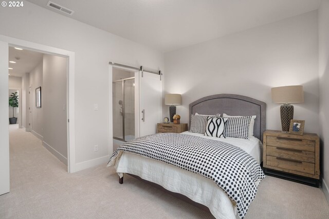 bedroom featuring baseboards, a barn door, visible vents, and light colored carpet