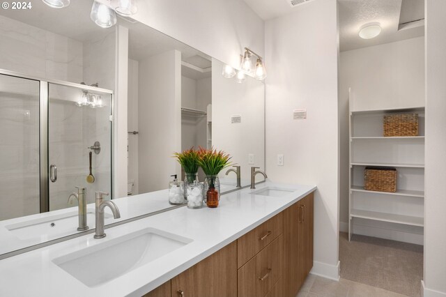 bathroom featuring a shower with door, vanity, and tile patterned flooring