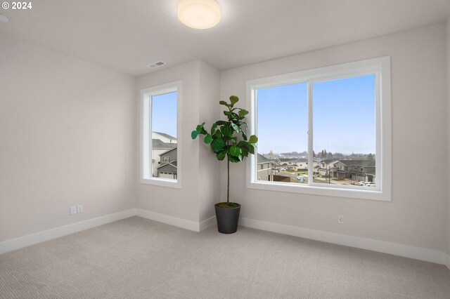 spare room featuring light carpet, baseboards, and visible vents