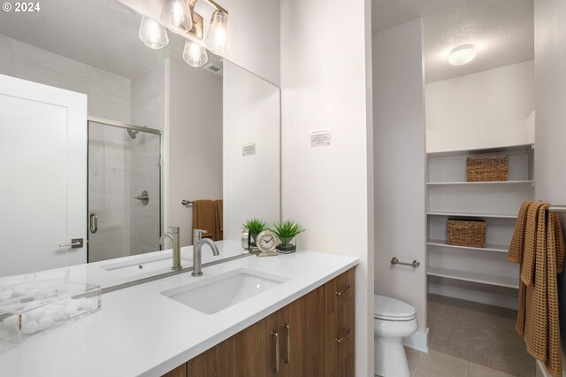 bathroom featuring tile patterned floors, vanity, toilet, and a shower with door