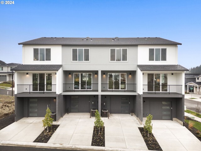 back of house with a garage, concrete driveway, and stucco siding