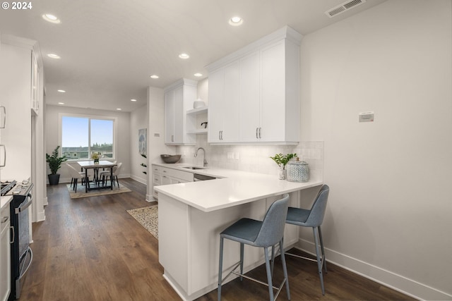 kitchen with a breakfast bar area, visible vents, white cabinetry, light countertops, and gas range