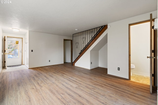 unfurnished living room with a textured ceiling and light hardwood / wood-style flooring