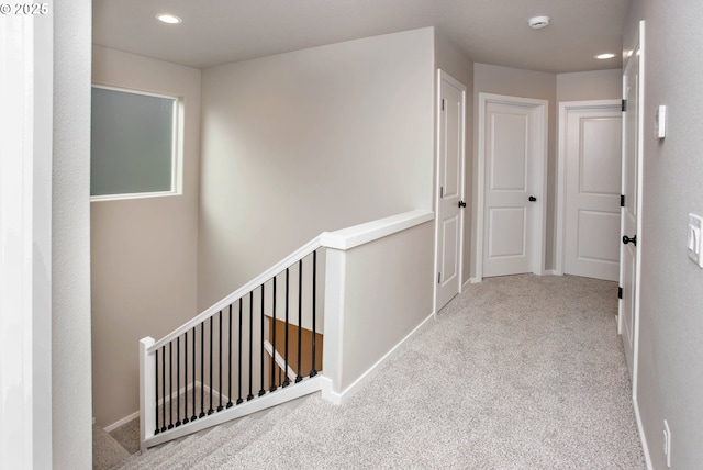 hall with baseboards, carpet, an upstairs landing, and recessed lighting