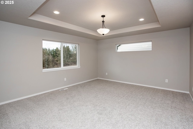 carpeted empty room featuring recessed lighting, a raised ceiling, visible vents, and baseboards