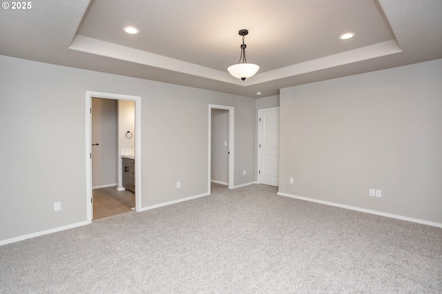 interior space with a tray ceiling, carpet flooring, baseboards, and recessed lighting