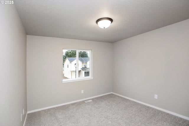 empty room featuring carpet, a textured ceiling, visible vents, and baseboards