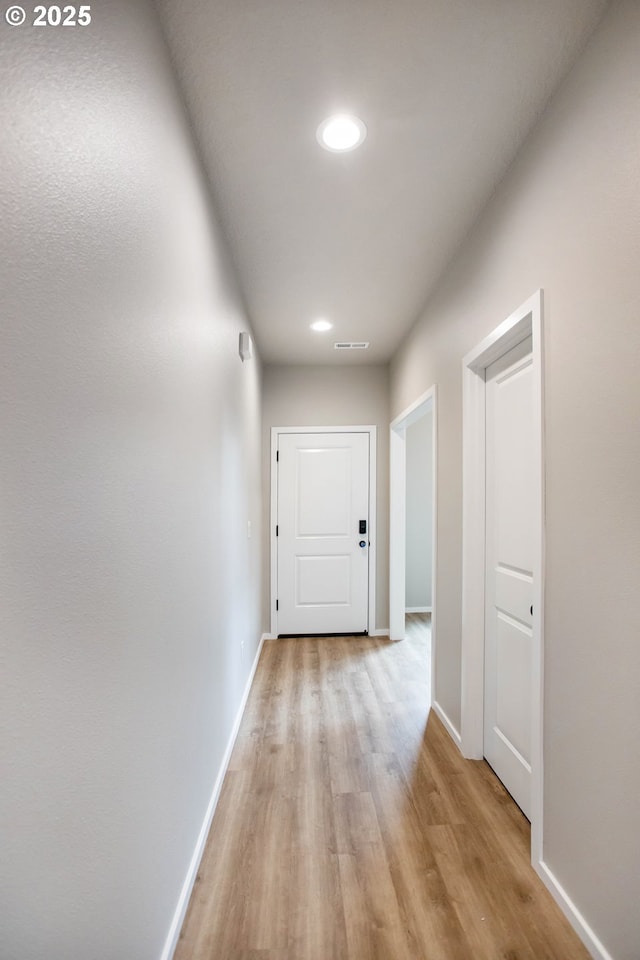 corridor featuring light wood-style floors, recessed lighting, visible vents, and baseboards