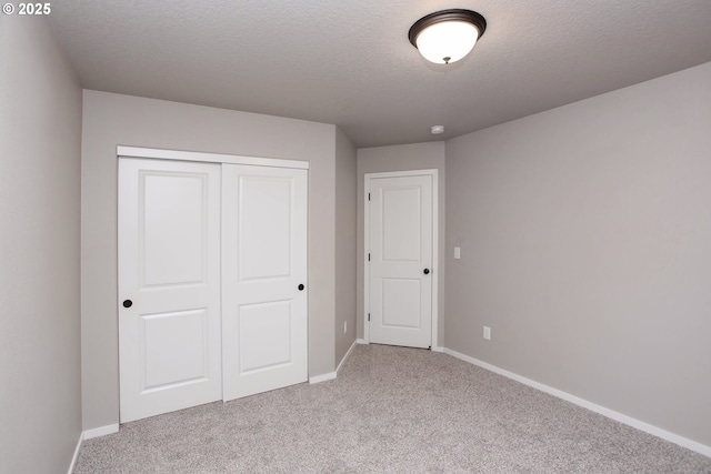 unfurnished bedroom with carpet, a closet, and baseboards