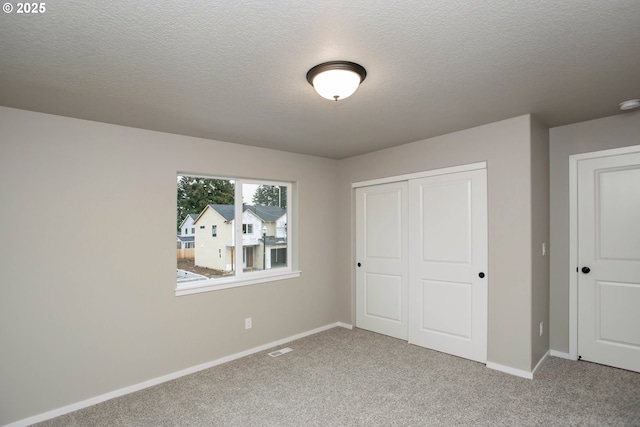 unfurnished bedroom with carpet floors, baseboards, visible vents, and a closet