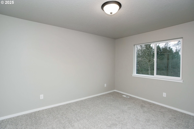 unfurnished room featuring a textured ceiling, carpet floors, visible vents, and baseboards