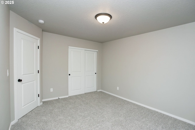 unfurnished bedroom featuring a textured ceiling, carpet floors, a closet, and baseboards