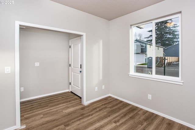 unfurnished room featuring a textured ceiling, baseboards, and wood finished floors