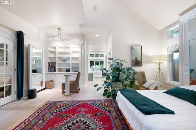 bedroom with light wood-type flooring, track lighting, and high vaulted ceiling