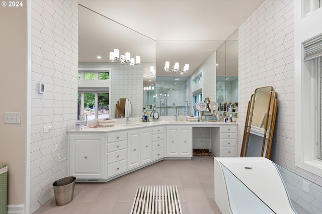 bathroom with an inviting chandelier, tile patterned flooring, a shower with door, vanity, and tile walls