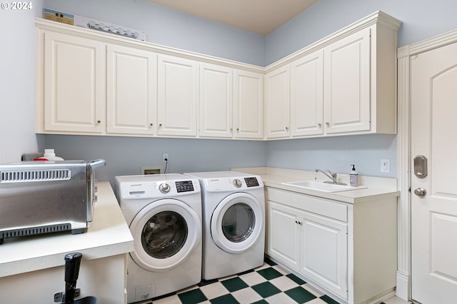 clothes washing area with cabinets, washer and clothes dryer, and sink