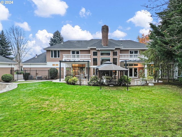 rear view of house featuring a gazebo, a balcony, a patio, and a lawn