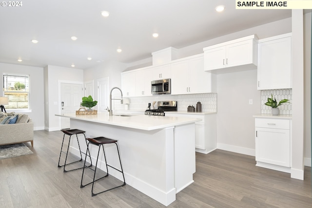 kitchen with sink, a kitchen island with sink, white cabinetry, appliances with stainless steel finishes, and light hardwood / wood-style floors