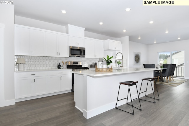 kitchen with a center island with sink, appliances with stainless steel finishes, dark hardwood / wood-style flooring, and white cabinetry