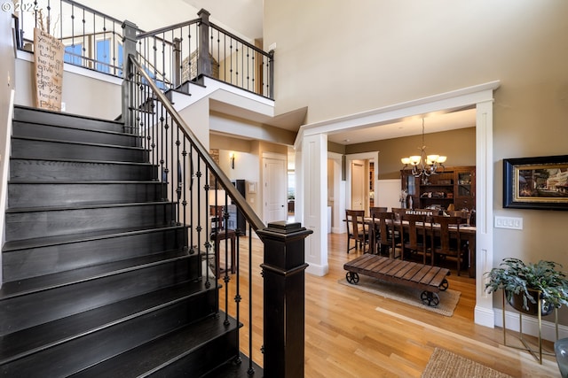 staircase with hardwood / wood-style flooring, a high ceiling, and a chandelier