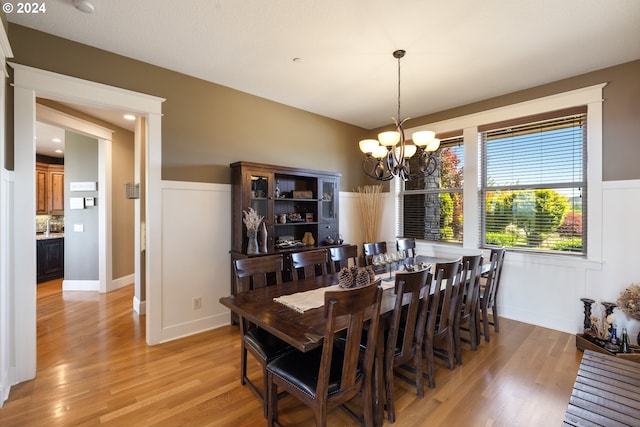 dining room with light hardwood / wood-style flooring and an inviting chandelier