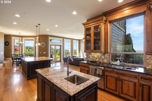 kitchen with stainless steel dishwasher, a kitchen island with sink, and sink